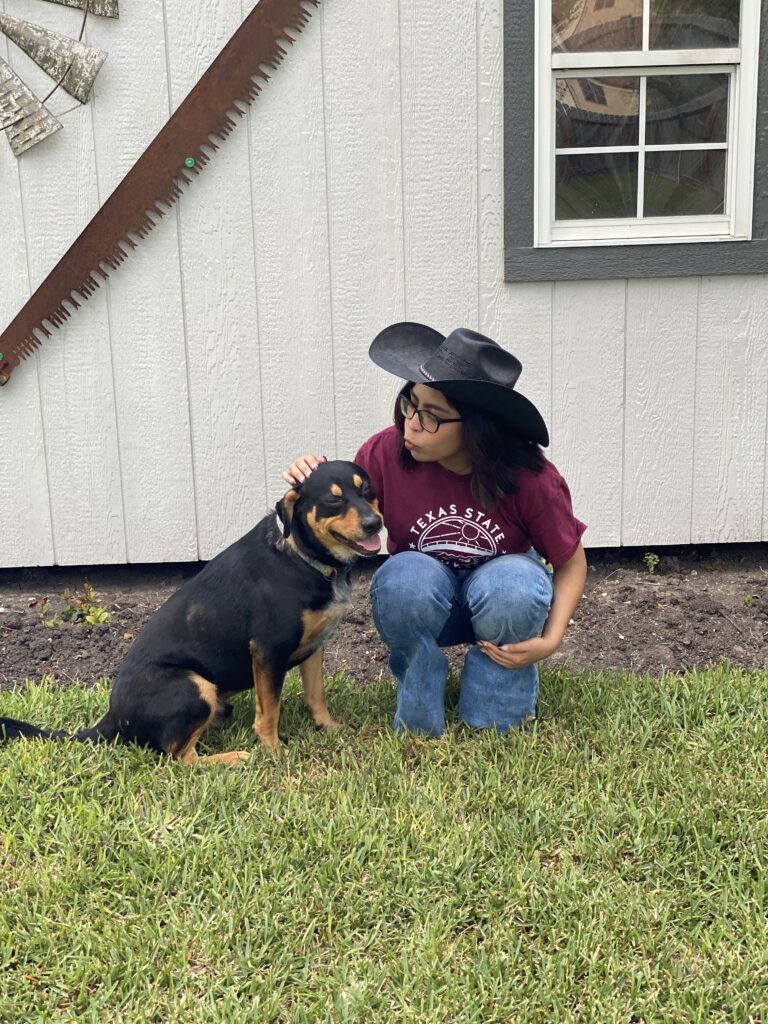 Black and brown dog with a girl posing for a picture. 